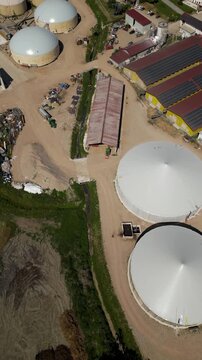 Biogas Plant Aerial View: An aerial perspective reveals a modern biogas production facility, featuring large, white digester tanks and industrial buildings.