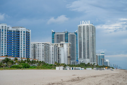 Luxury high rise condominiums along the Miami Beach coastline. Wide view of modern skyscraper architecture and sandy beach under a cloudy sky in Miami Florida USA.