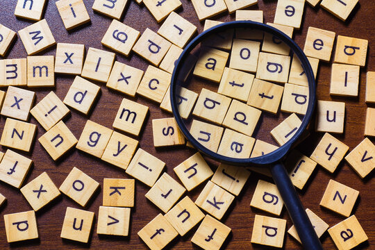 English letters are scattered on a wooden table, representing an idea about learning the English language.