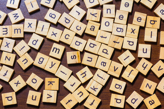 English letters are scattered on a wooden table, representing an idea about learning the English language.