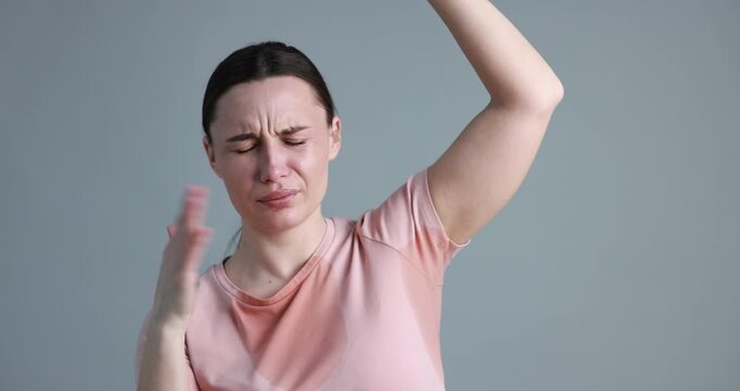 Woman suffering from sweating on grey background