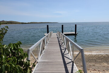Obraz premium long narrow wooden walkway to small dock in strong tropical sunshine (close-up) 3509
