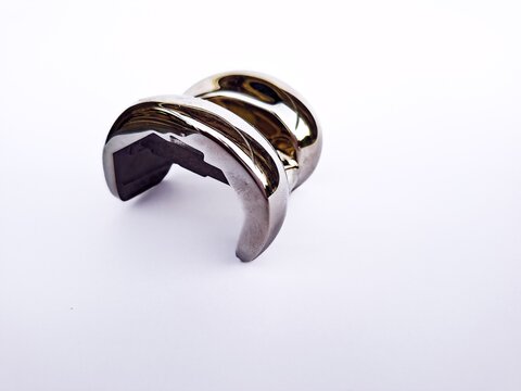 Close-up of a metallic femoral component for total knee replacement surgery. Orthopedic artificial knee joint implant prosthesis isolated on a white background. Medical healthcare concept