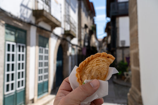 Tortas de Guimar&atilde;es held in hand viewed in front of a defocused city street