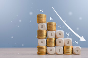 Wooden blocks with down arrows and golden coins arranged in a declining graph pattern against a blue background. Concept for mortgage rate reduction, deflation and financial crisis. © vadish