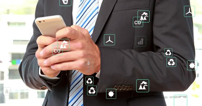 Businessman holding phone, tapping and scrolling causing floating data icons for eco finance data
