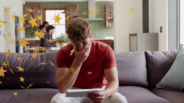 Man carrying mail walking to sofa in home unfolding and reviewing mail while golden stars drifting