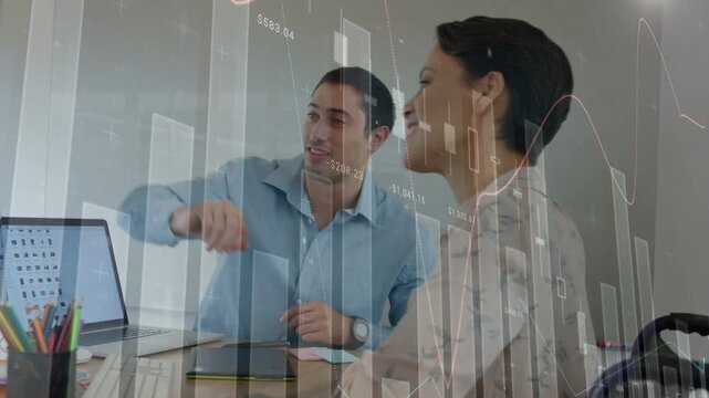 Two colleagues pointing at monitor, reviewing overlaying financial charts and agreeing on numbers