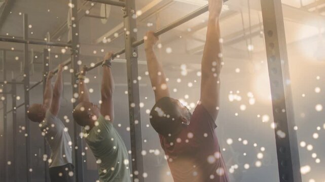 Three men reaching up, gripping rig and doing pull-ups for fitness, particles covering bodies