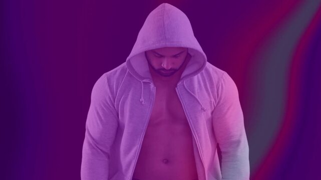 Man raising hood with hand motion, showcasing fashion hoodie while neon waves overlaying torso