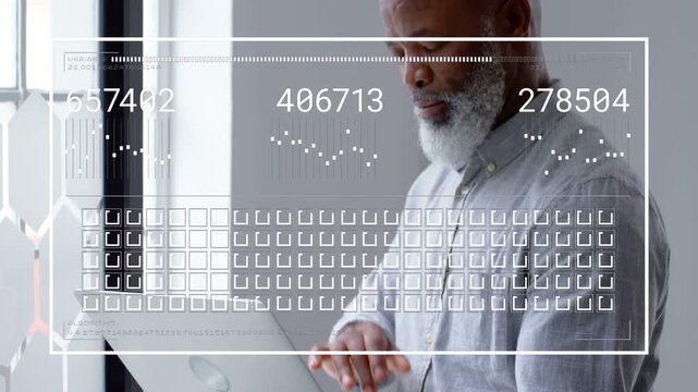 Businessman holding laptop by window typing and generating numeric charts, icons analyzing metrics