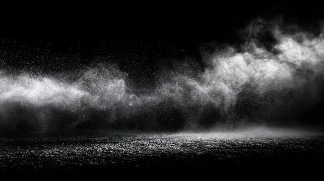 This abstract image features a white dust cloud or smoke effect against a dark, black background. The particles are in motion, creating a dynamic and atmospheric texture across the frame.