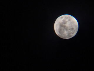 Obraz premium Full moon shining brightly in a Pitch black night sky. Detailed astrophotography captures the moon's cratered surface against complete darkness. Perfect for space and night themes.