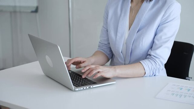 Businesswoman's hands typing on a laptop, performing data entry, communicating via email, or engaging in a productive online task at an office desk, highlighting focus and efficiency