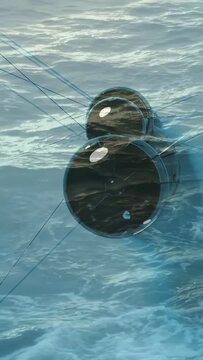Vertical video: Camera panning, three clear pods rotating, showing hubs and taut cables over sea