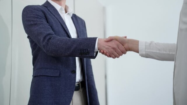 Two business people shaking hands, concluding a professional agreement or greeting, representing successful negotiation, partnership, and trust in a collaborative workplace setting