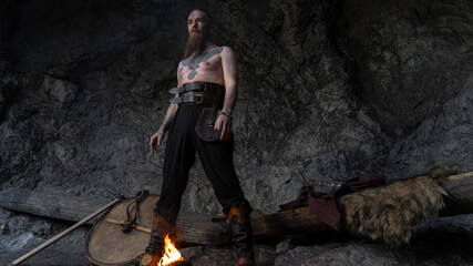 A rugged Viking warrior stands confidently amidst a rocky landscape, gazing intently at the viewer with a fiery determination. © horimono