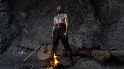 A muscular, bearded Viking stands confidently within a rocky cave, adorned with traditional attire and weaponry. © horimono