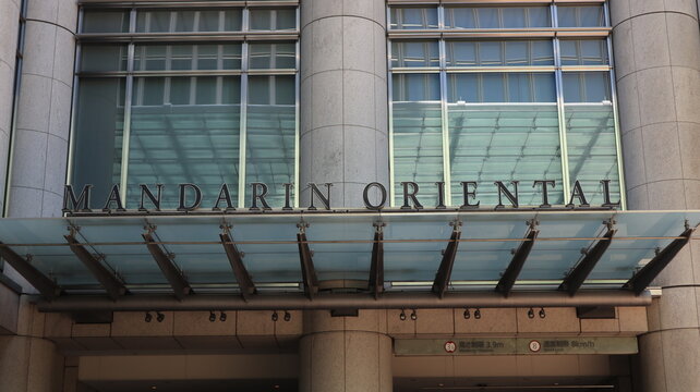 Mandarin Oriental Tokyo luxury hotel building exterior featuring modern glass canopy and corporate logo signage on the Nihonbashi Mitsui Tower facade - Tokyo, Japan, October 15, 2023