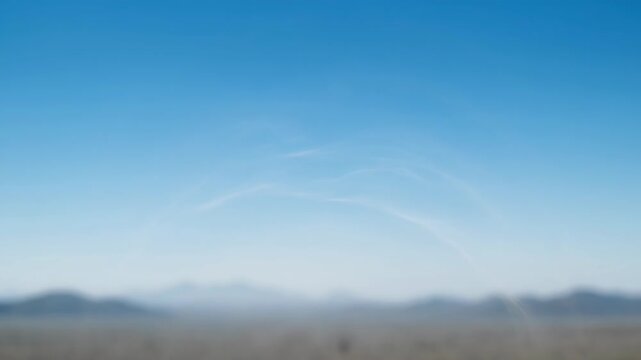 Vast blue sky stretches over a hazy, distant mountain range under a bright, clear day.