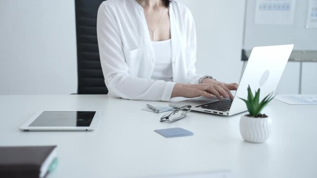 Businesswoman writing important notes on sticky paper while planning tasks on laptop, organizing workspace for efficient project management and productivity
