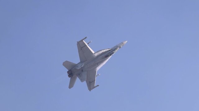 A military fighter jet flying in clear blue sky, launching flares from its fuselage for defense, demonstrating advanced aerial maneuvers.
