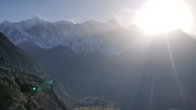 Spectacular God rays and sunbeams shining through clouds onto the sharp summit of Namcha Barwa mountain in Tibet.
