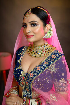 Stunning Indian bride wearing a traditional bridal lehenga with heavy gold jewellery, smiling gracefully in studio lighting