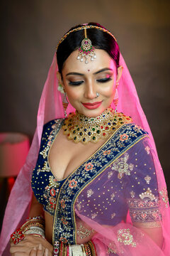 Stunning Indian bride wearing a traditional bridal lehenga with heavy gold jewellery, smiling gracefully in studio lighting