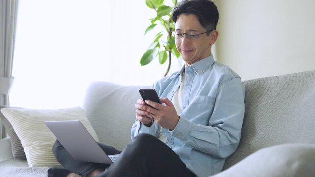 パソコンとスマートフォンを使う男性のライフスタイルイメージ, Man Using Laptop and Smartphone at Home Lifestyle Concept