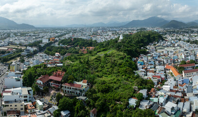 Obraz premium Nha Trang, Vietnam - An aerial view captures the sprawling cityscape with lush green hills and a prominent white Buddha statue at Long Son Pagodaoverlooking the urban landscape.