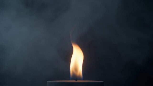 Close-up of a single burning candle flame with smoke against dark background