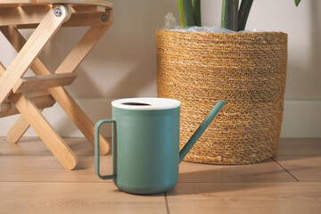 Modern watering can near plant pot and wooden stool © Towfiqu Barbhuiya 