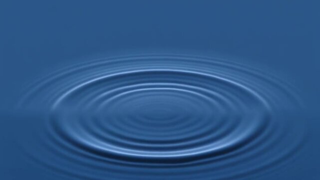 Close-up of water ripple from single drop hitting calm blue surface