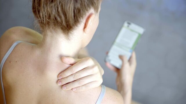 Woman suffering from neck pain while looking at phone