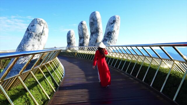 Asian female tourist walking on golden bridge in Ba Na hills, Danang, Vietnam.