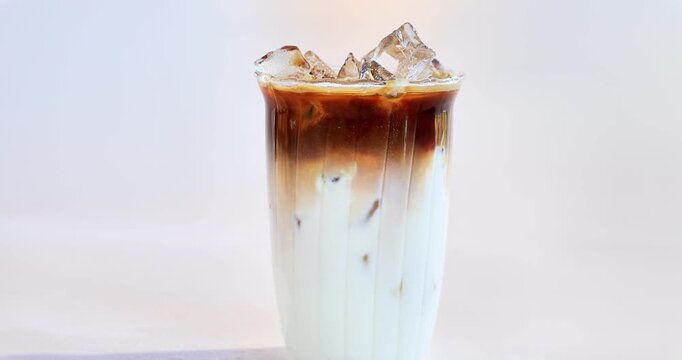 A close-up of a layered iced coconut latte in a glass.