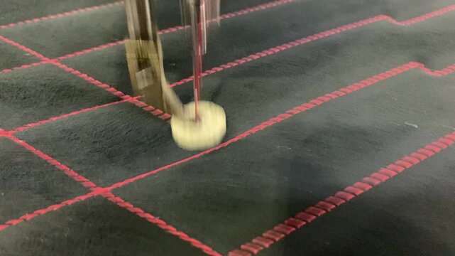 The sewing machine is sewing on a piece of leather using a beautiful red thread