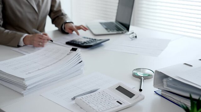 Businesswoman hands organizing stack of papers with binder clips, working on financial documents and official reports in office. Audit and taxes concept