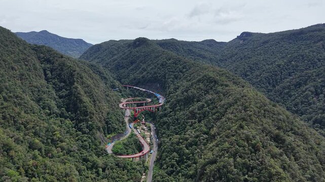 a flyover in a valley between green mountains in West Sumatra, Indonesia, named "Kelok Sembilan"