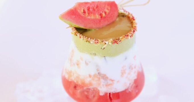 A red guava slice topped with a three-layered guava matcha iced drink.