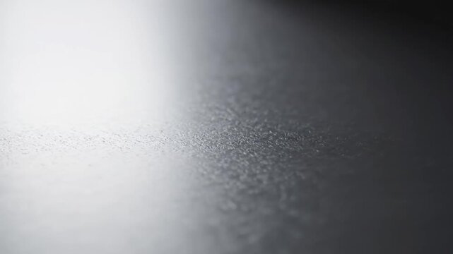 Abstract dark grey textured surface with soft light gradient.