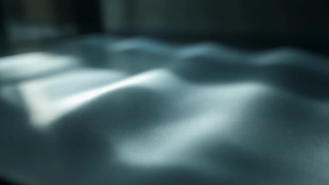 Abstract light reflection patterns on textured surface, soft focus, cool tones