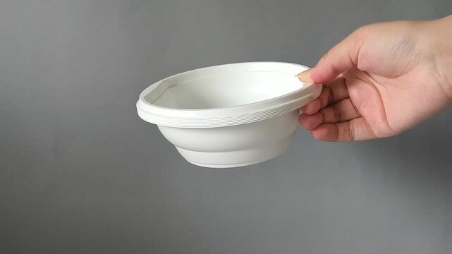 Deep disposable plastic plate in hand on gray background. Set of dishes