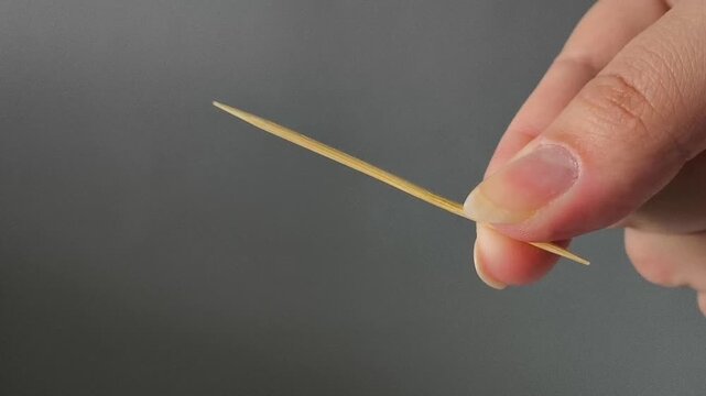 Disposable wooden toothbrush in hand on a gray background. Dental care