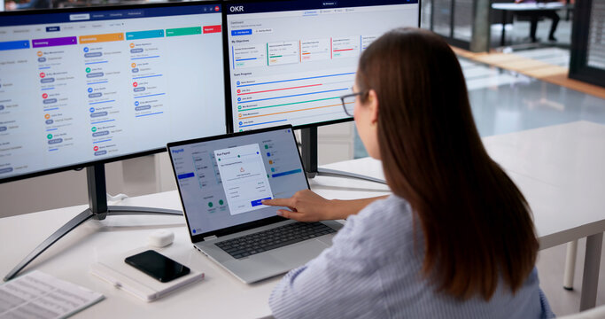 HR Manager Checks Payroll Data On Multiple Screens