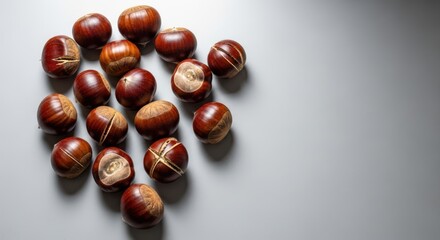 Obraz premium Group of fresh brown chestnuts scattered on a light gray background
