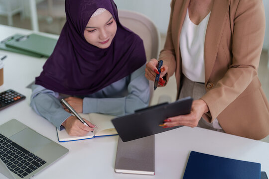 Muslim businesswoman hijab consulting coworker office meeting discussing project strategy tablet laptop notebook professional workplace collaboration teamwork