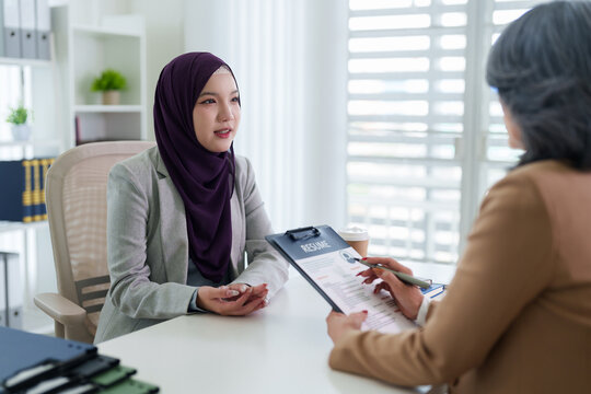 Asian Muslim women job interview professional business meeting office recruiter review resume candidate apply for employment opportunity discussion at modern