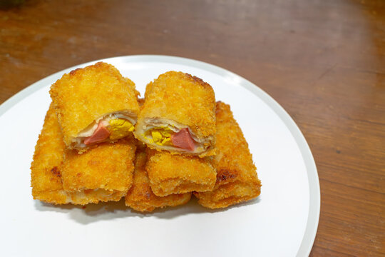 Risol Mayo or Risoles Mayo on a plate over a wooden table. Thin Crepes Rolled with Egg, mayonaise and Sausage Inside, Deep fried with Bread Crumb Coating